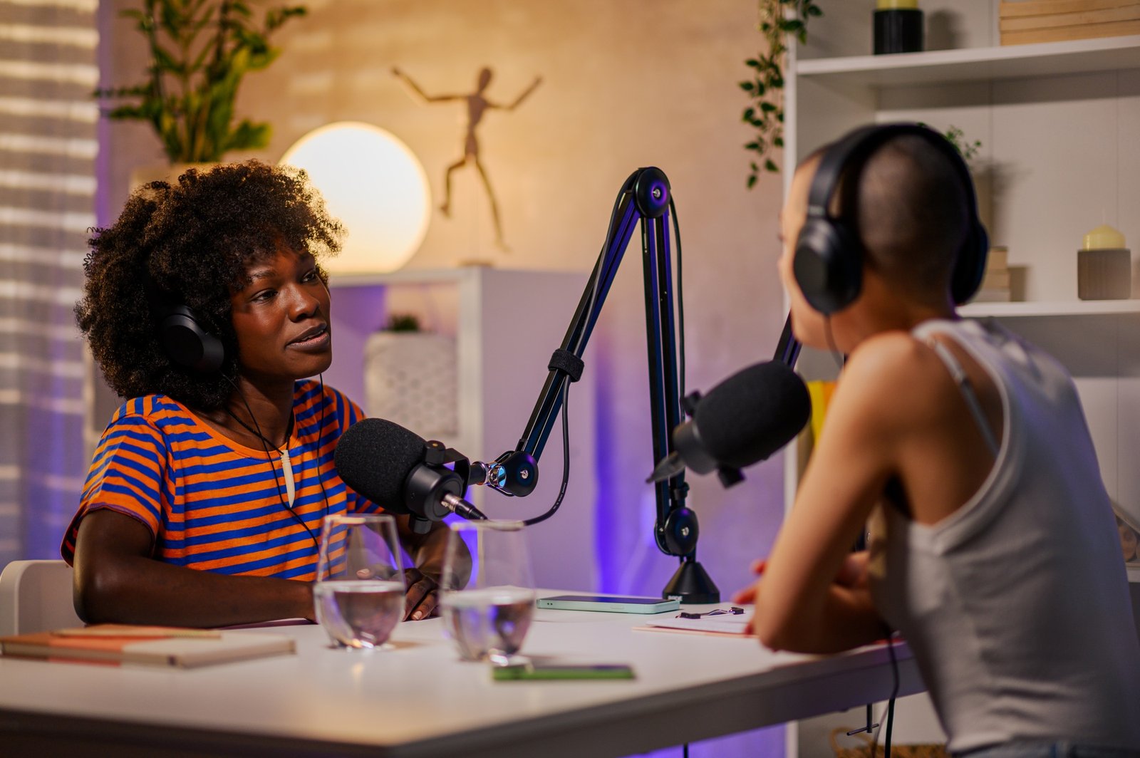 Two gen z girls are sitting in a home recording studio and filming a podcast
